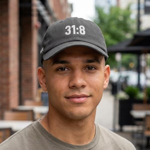 Könnte beinhalten: Dunkelgraue Baseballkappe mit dem weißen Text "31:8". Die Kappe hat einen gebogenen Schirm und besteht aus einem weichen Stoff. Die Kappe wird von einer Person getragen.