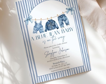 May include: A rectangular baby shower invitation card featuring a blue and white vertical striped border. The center displays watercolor illustrations of denim overalls, a jacket, and jeans hanging on a clothesline with blue bows and the text A BLUE JEAN BABY is on the way, followed by event details for Shaylynn Johnson.