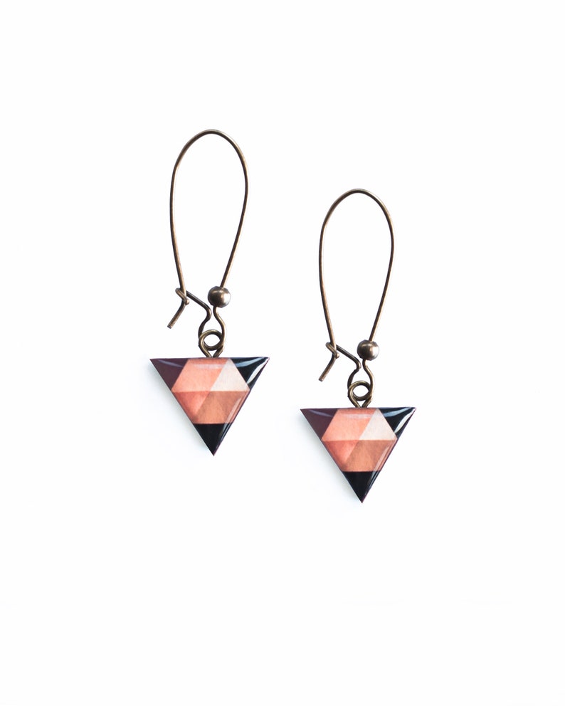 May include: A pair of triangle-shaped earrings with a geometric pattern in shades of brown, pink, and black. The earrings are made of metal and have a hook closure.