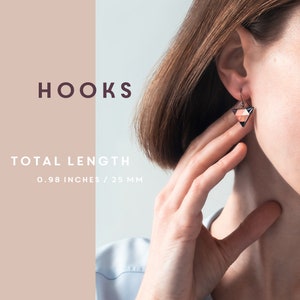 May include: A pair of geometric triangle earrings with a black, white, and pink color scheme. The earrings are made of wood and have a total length of 0.98 inches or 25 mm.