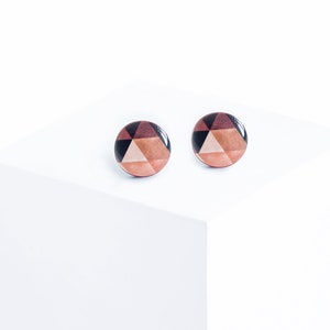 Può includere: Un paio di orecchini rotondi con un motivo geometrico in tonalità di marrone, nero e rosa.