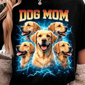 Puede incluir: Camiseta negra con el texto "DOG MOM" en naranja y blanco. La camiseta presenta un gráfico de cinco perros golden retriever rodeados de rayos azules.