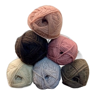 May include: A collection of seven balls of yarn in a range of colours. The shades include pale pink, dark brown, dusty rose, cream, light grey, and olive green. The yarn is tightly wound, and the balls are arranged in a pyramid shape.