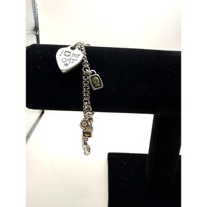 Pode incluir: Uma pulseira de prata com v&aacute;rios berloques. A pulseira apresenta um berloque em forma de cora&ccedil;&atilde;o com o texto "I my CAT" e uma estrela. Outros berloques incluem um gato, um peixe e elementos decorativos.