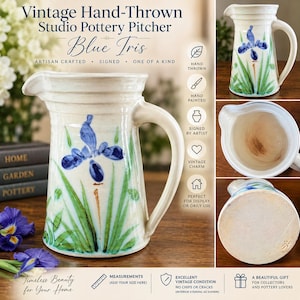 Può includere: Una brocca in ceramica vintage realizzata a mano, decorata con un fiore di iris blu dipinto a mano e foglie verdi su un corpo color crema. La brocca presenta un manico curvo, un beccuccio per versare e una firma sulla base circolare.