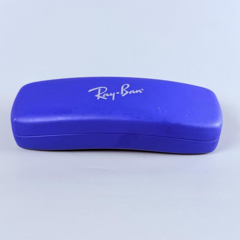Estuche rígido azul para gafas Ray-Ban con interior rojo y acabado mate tipo concha. imagen 4