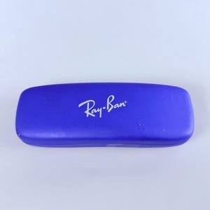 Estuche rígido azul para gafas Ray-Ban con interior rojo y acabado mate tipo concha. imagen 2