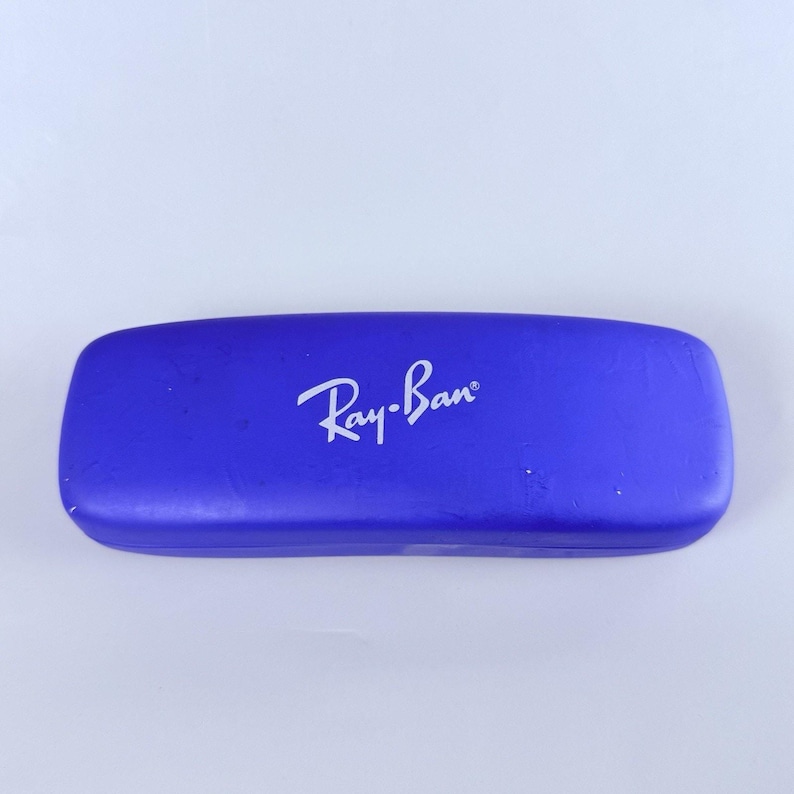 Estuche rígido azul para gafas Ray-Ban con interior rojo y acabado mate tipo concha. imagen 2