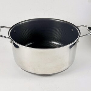May include: A stainless steel cooking pot with two curved handles. The interior is dark grey with a textured surface. The pot has a wide opening and a rounded base, suitable for various cooking tasks.