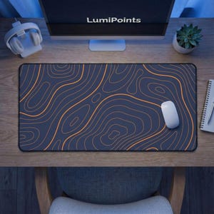 Peut inclure: Tapis de souris rectangulaire bleu foncé avec des lignes topographiques orange. Une souris d'ordinateur blanche repose sur le tapis. Le texte "LumiPoints" est visible sur l'écran de l'ordinateur.