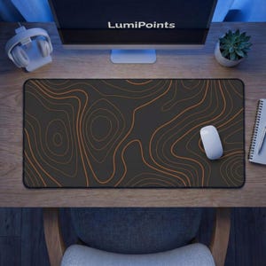 May include: A black rectangular mousepad with a topographic map design in shades of orange. A white computer mouse rests on the pad. The word "LumiPoints" is visible on the computer monitor.
