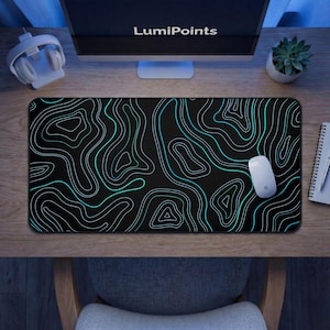 May include: A black rectangular mouse pad with a topographic design in white and teal lines. A white computer mouse rests on the pad. The word "LumiPoints" is visible on the computer monitor.