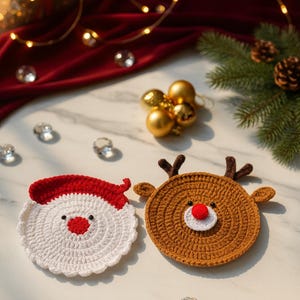 Puede incluir: Dos posavasos navideños hechos a mano con ganchillo. Uno es blanco con un gorro de Papá Noel rojo y el otro es marrón con cuernos de reno y una nariz roja. Los posavasos están sobre una superficie blanca con adornos navideños.