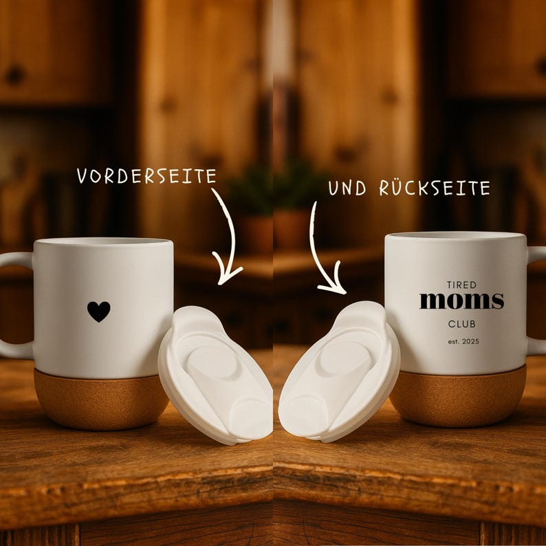 K&ouml;nnte beinhalten: Zwei wei&szlig;e Keramikbecher mit Korkb&ouml;den. Einer hat ein schwarzes Herz, der andere den Text "TIRED MOMS CLUB est. 2025". Zwei wei&szlig;e Kunststoff-Becherdeckel liegen vor den Bechern. Der Hintergrund ist eine Holzoberfl&auml;che.