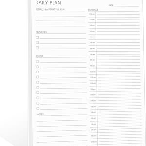 May include: A white spiral-bound daily planner with the text "DAILY PLAN" at the top. The planner includes sections for priorities, to-do lists, and a schedule from 12:00 am to 11:00 pm. There is also a space to write "TODAY, I AM GRATEFUL FOR".