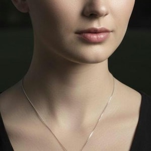 May include: A silver necklace with a triangular pendant. The pendant features a starfish and seashells encased in clear resin over a blue background. The necklace is worn by a person wearing a black top.