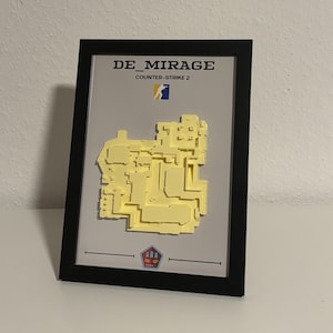 May include: Framed artwork featuring a yellow 3D map of the "DE_MIRAGE" Counter-Strike 2 level. The black frame surrounds a gray background with the game's title and logo. A detailed, layered design adds depth to the map.