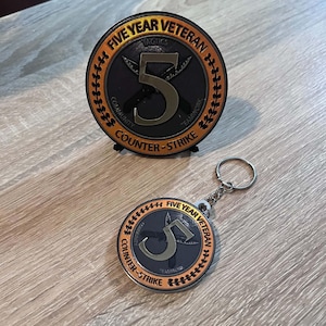 May include: A circular Five Year Veteran Counter-Strike coin with a black centre, a large silver number 5, and two crossed knives. The orange border features the text Five Year Veteran and Counter-Strike. A matching keychain is also included.