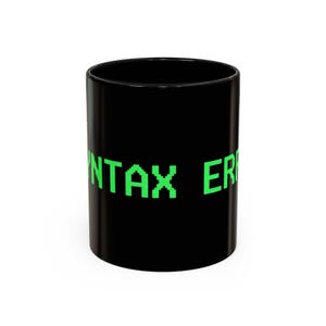 May include: A black ceramic coffee mug with the words "SYNTAX ERROR" in bright green, pixelated font. The mug is cylindrical and has a glossy finish, suitable for hot or cold beverages.
