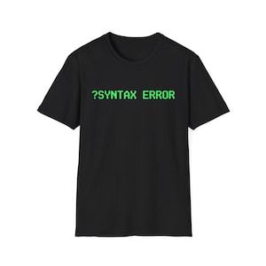 May include: Black t-shirt with the text "?SYNTAX ERROR" in green, pixelated font. The shirt is a basic crew neck style, suitable for casual wear. The text is centered on the chest.