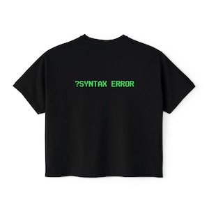 May include: Black t-shirt with the text "?SYNTAX ERROR" in green, a humorous design. The shirt has a classic crew neck and short sleeves, suitable for casual wear.