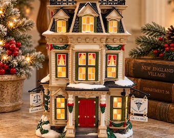 May include: A miniature building with a red front door, lit windows, and snow-covered roof. Two hanging signs read "Attorney Benjamin Hardy" with a scale icon and "Practice of General Medicine Dr. T.H. Hale" with a caduceus symbol.
