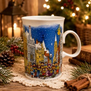 May include: A white ceramic mug featuring a colorful illustration of a group of people singing carols in a snowy town square at night. The scene includes detailed buildings, a street lamp, and a crescent moon against a deep blue starry sky.