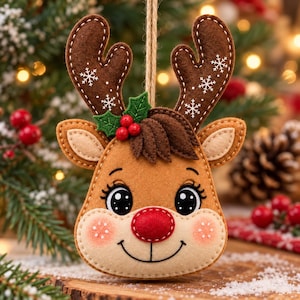 Pode incluir: Um enfeite de rena em feltro com chifres castanhos bordados com flocos de neve brancos, nariz vermelho, folhas de azevinho verdes com bagas vermelhas e rosto bege com olhos e sorriso costurados a preto, suspenso por um cordão castanho.