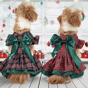 May include: Two dogs wearing matching red, black, and green plaid dresses with large green satin bows. The dresses have a flared skirt and a green satin trim. The dogs are positioned in front of a festive holiday backdrop.