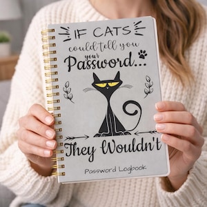 Puede incluir: Un cuaderno de contraseñas gris con espiral y detalles dorados. La portada presenta una ilustración de gato negro con ojos amarillos y el texto "If cats could tell you your password... They wouldn't." Las palabras "Password Logbook" están en la parte inferior.