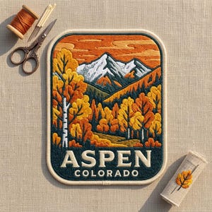 May include: A rectangular embroidered patch featuring a mountain landscape with snow-capped peaks, orange and yellow autumn trees, and the text ASPEN COLORADO. The patch is accompanied by a spool of orange thread, needles, and a small fabric scrap.