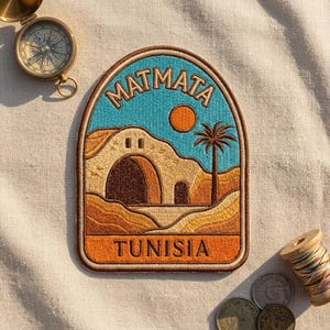 May include: An embroidered patch featuring a desert landscape with a tan arched structure, a palm tree, and an orange sun against a blue sky. The text MATMATA is arched at the top and TUNISIA is printed in an orange banner at the bottom.