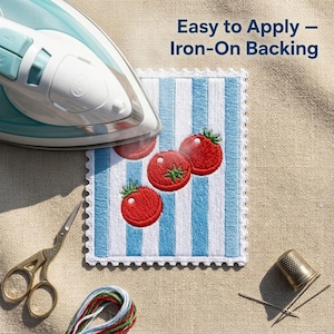 Op de afbeelding: Een rechthoekige geborduurde patch met drie rode tomaten op een wit en lichtblauw gestreepte achtergrond met een geschulpte rand. De tekst "Easy to Apply &ndash; Iron-On Backing" is zichtbaar. Een strijkijzer, schaar, garen en een vingerhoed zijn aanwezig.