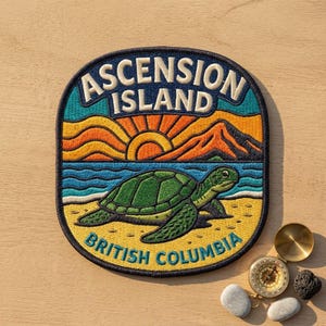 May include: A circular embroidered patch featuring a green sea turtle on a sandy beach with blue ocean waves, orange mountains, and a yellow sun. The text reads ASCENSION ISLAND at the top and BRITISH COLUMBIA at the bottom in bold lettering.