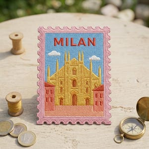 May include: A rectangular embroidered patch shaped like a postage stamp with a pink scalloped border. The design features a yellow cathedral in Milan under a light blue sky with white clouds, the word MILAN in red, and two small red buildings.