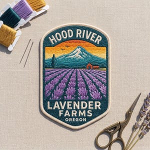 May include: An embroidered patch featuring a landscape of purple lavender fields, a red barn, and a snow-capped mountain under an orange sky. The text reads HOOD RIVER LAVENDER FARMS OREGON. The patch is surrounded by embroidery floss, needles, and scissors.