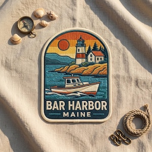 May include: An embroidered patch featuring a coastal scene with a lighthouse, a house, and a boat on the water. The sky is orange and yellow with a circular sun. The text reads BAR HARBOR MAINE in white capital letters against a dark blue background.