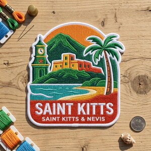 May include: An embroidered patch featuring a tropical landscape with a green clock tower, yellow buildings, a palm tree, and a mountain against an orange sky. The text reads SAINT KITTS SAINT KITTS & NEVIS in white letters on a red background.