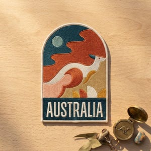 May include: An arched embroidered patch featuring a stylized white kangaroo leaping across a landscape of orange, teal, and gold shapes under a pale blue sun. The word AUSTRALIA is stitched in white capital letters on a dark teal rectangular base.