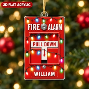 May include: A rectangular 2D flat acrylic ornament featuring a red fire alarm pull station design. The text reads FIRE ALARM, PULL DOWN, and WILLIAM. A string of colorful Christmas lights is draped across the front of the alarm station.