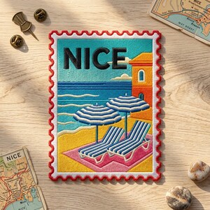 May include: A rectangular embroidered patch shaped like a postage stamp featuring the word NICE in black letters. The design depicts a beach scene with two blue and white striped umbrellas, two matching lounge chairs, and an orange building.