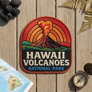 May include: An embroidered patch featuring a volcanic eruption with orange and red concentric circles in the background, green hills, and the text HAWAII VOLCANOES NATIONAL PARK in white and blue lettering on a black background.