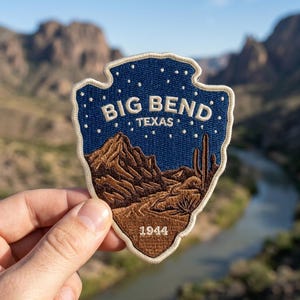 May include: An arrowhead-shaped embroidered patch featuring a dark blue night sky with white stars above a brown desert landscape with mountains and a cactus. The text reads BIG BEND TEXAS and 1944 in white thread with a cream-colored border.
