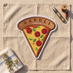 May include: A triangular pizza slice patch featuring yellow cheese, red pepperoni circles, and green basil leaves. The brown crust area is embroidered with the text NAPOLI ITALIA in white letters. The patch has a thick white border edge.