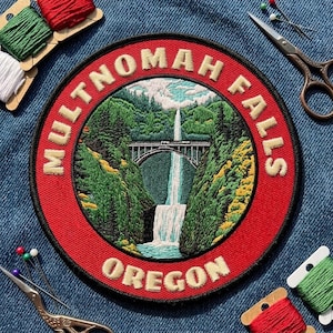May include: A circular embroidered patch featuring a landscape of Multnomah Falls in Oregon. The design includes a waterfall, a stone bridge, and green trees, surrounded by a red border with the text MULTNOMAH FALLS OREGON in cream letters.