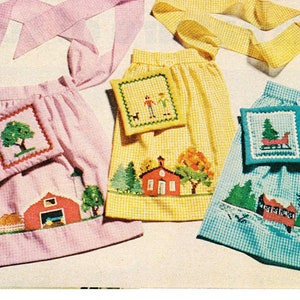 May include: Four gingham fabric aprons with embroidered designs. The aprons are pink, yellow, blue, and white. Each apron has a matching pocket with an embroidered design. The designs include a tree, a house, a family, and a sleigh.