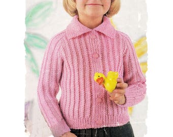 May include: A young girl wearing a pink knitted cardigan with a button-up front. She is holding a yellow rubber ducky toy.