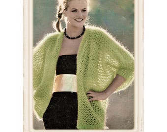 May include: A woman wearing a light green knitted cardigan with a black tank top and a silver belt. The cardigan has a loose fit and a delicate openwork pattern.