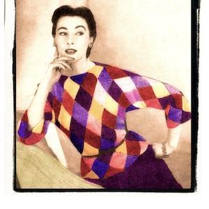 Könnte beinhalten: Eine Frau trägt einen bunten Diamantenmuster-Pullover mit einem lila Rock. Der Pullover hat eine Mischung aus roten, gelben, lila und weißen Quadraten.