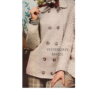 May include: A light beige double-breasted coat with a textured knit design and large buttons. The image also shows a brown hat, a patterned scarf, and the text "Yesterdays Magic". The coat is a vintage style.